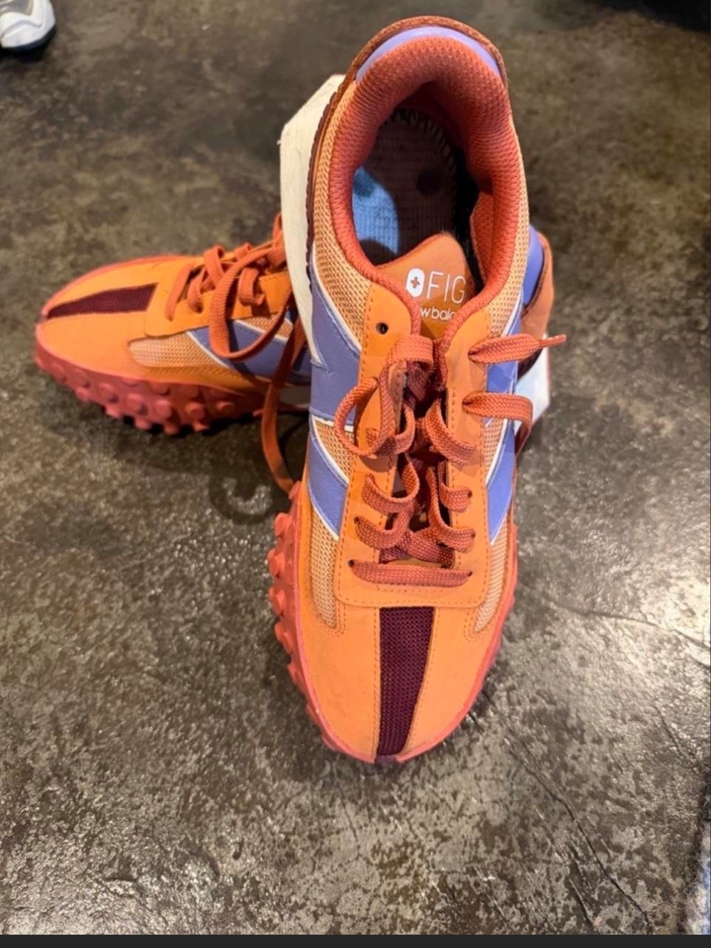 New Balance x FIGS XC-72 sneakers in an orange and purple colorway.